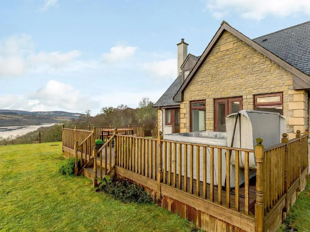 a house with a wooden fence and a hot tub at The Big Hoose in Achnahanat