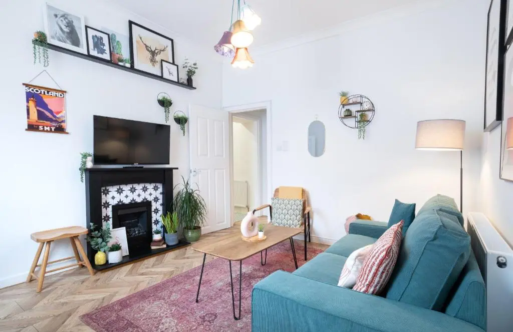 a living room with a blue couch and a fireplace at Macdonald Street Snug in Inverness