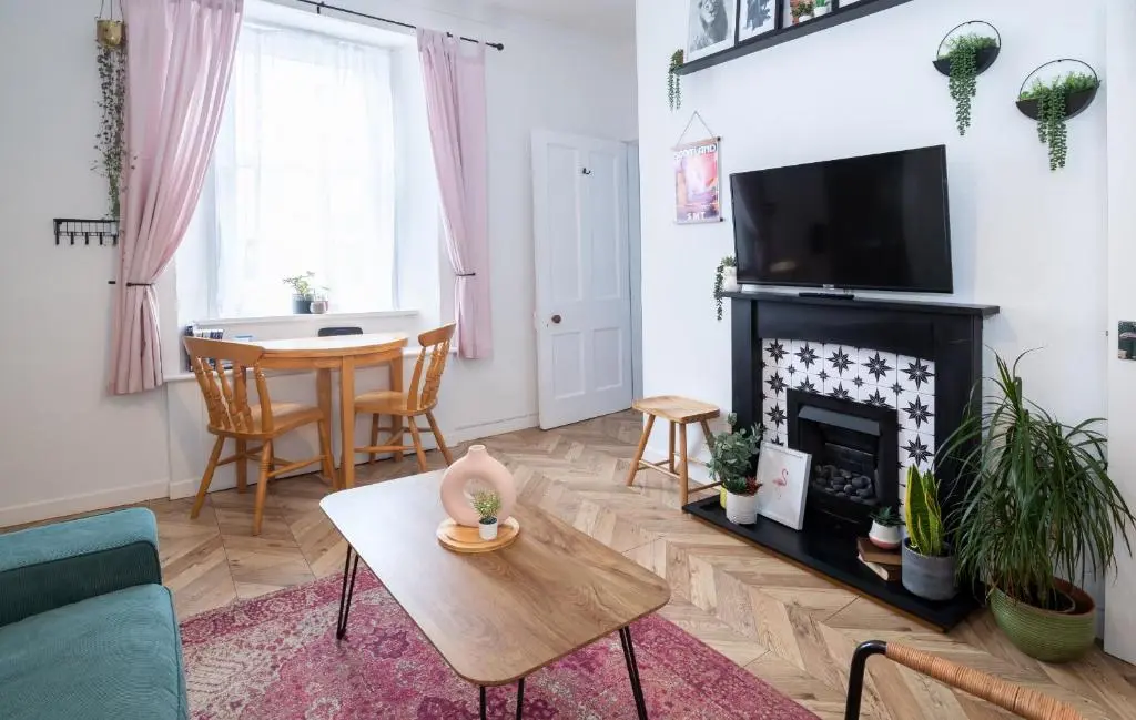 a living room with a fireplace and a table at Macdonald Street Snug in Inverness