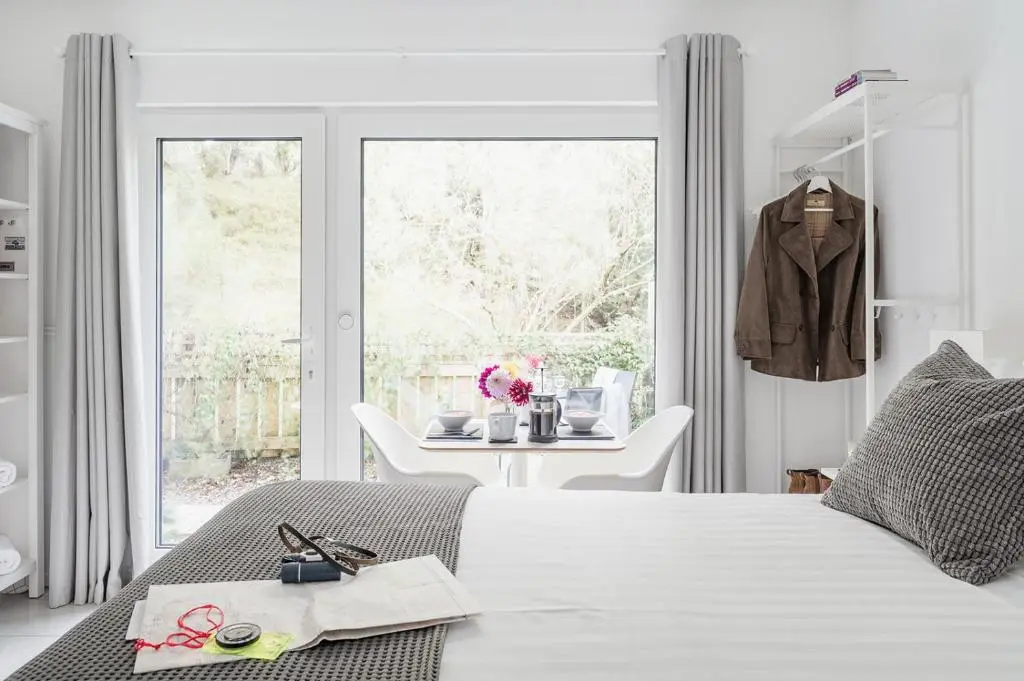 a white bedroom with a bed and a table at Siskin Guest Suite in Kinrara