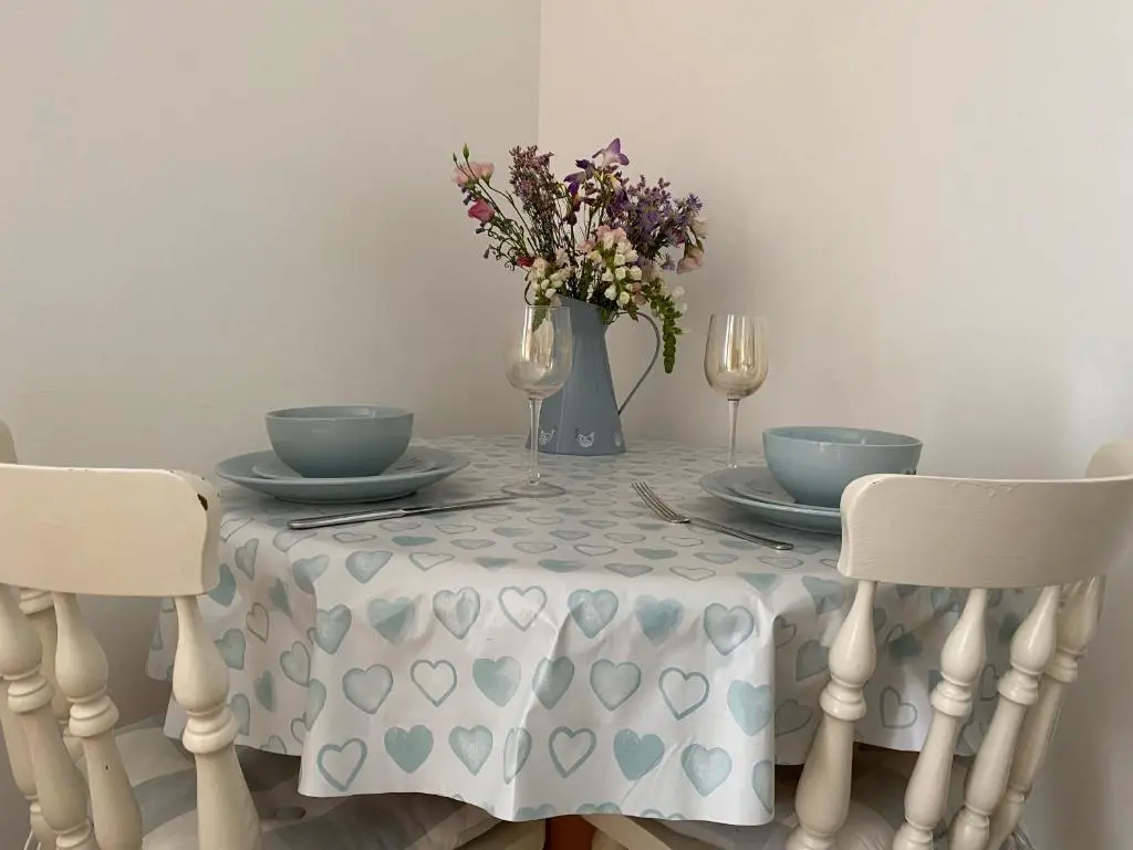 a table with a table cloth with a vase of flowers at The Den in Stuartfield