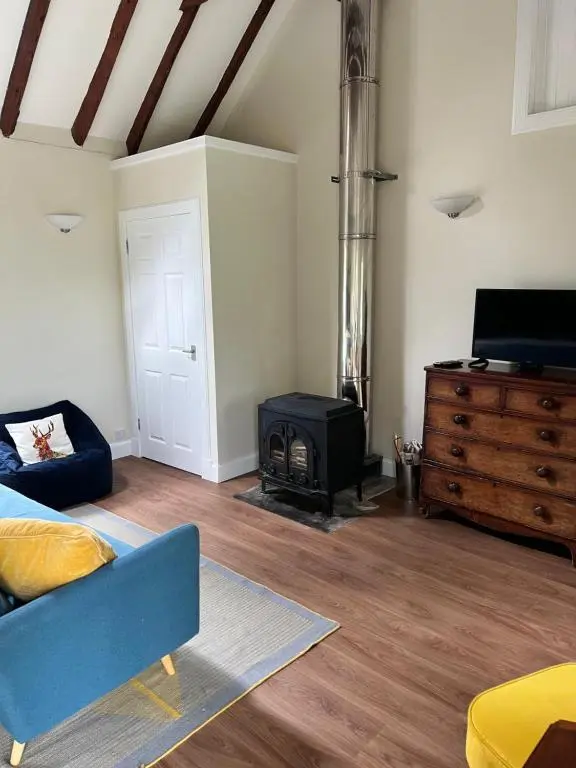 a living room with a blue couch and a stove at Blairbeg Cottage in Blairgowrie