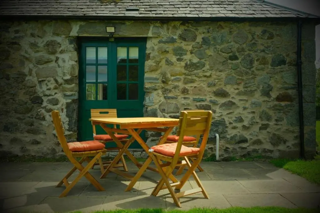 a wooden table and chairs in front of a building at Blairbeg Cottage in Blairgowrie