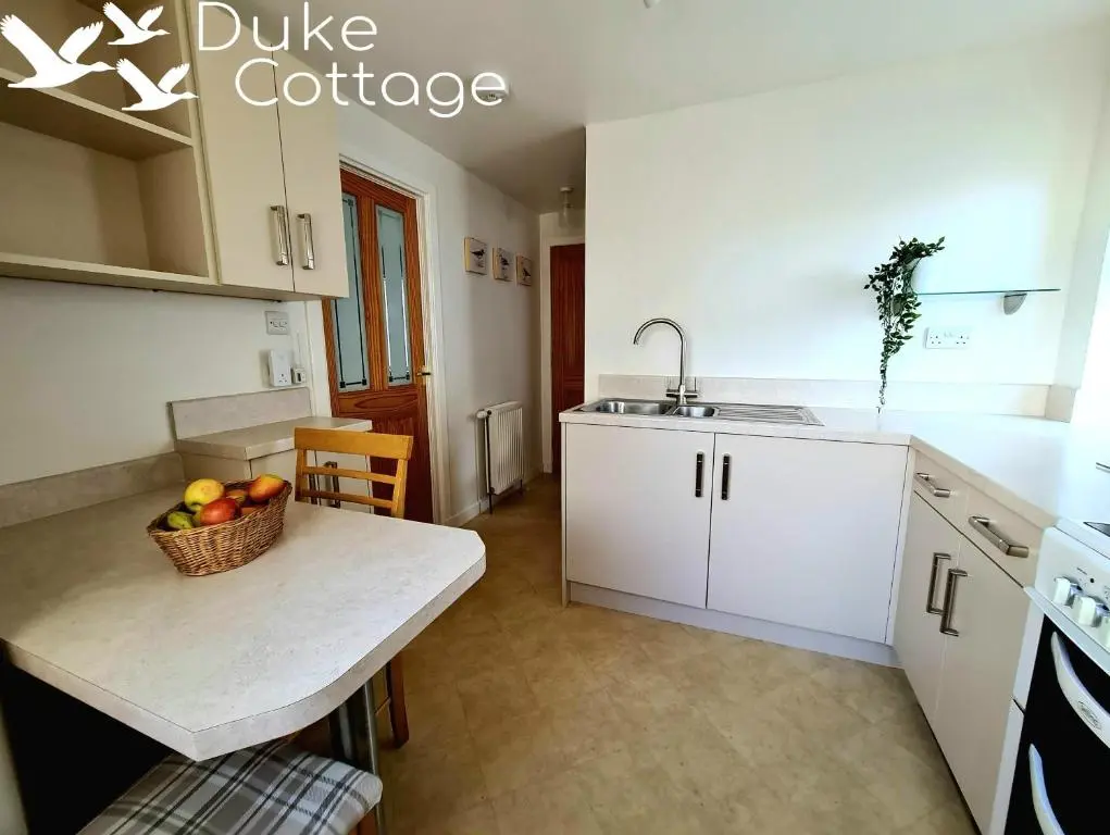 a kitchen with a table with a bowl of fruit on it at Duke Cottage in Fochabers