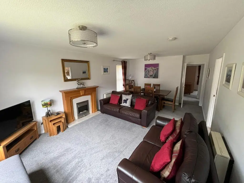 a living room with a couch and a fireplace at Cairngorm Cottage in Aviemore