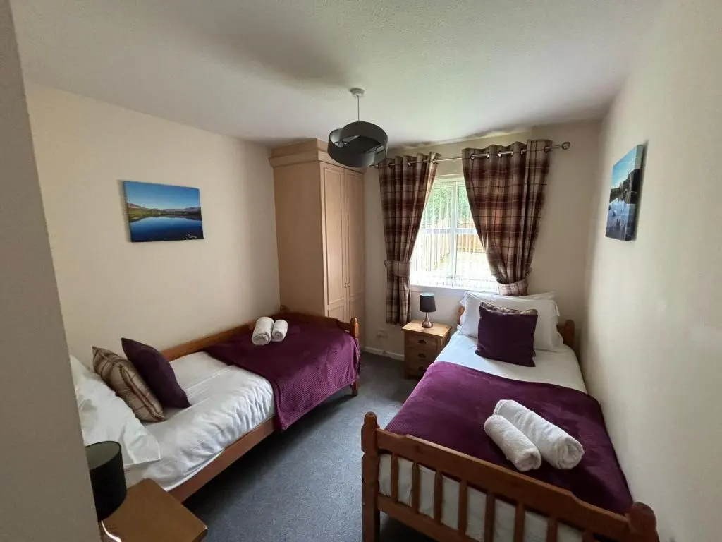 a bedroom with two beds and a window at Cairngorm Cottage in Aviemore