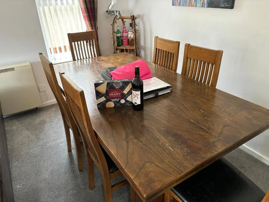a wooden table with a bottle of wine on it at Cairngorm Cottage in Aviemore
