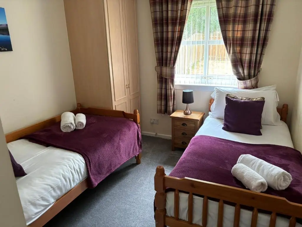 a bedroom with two beds and a window at Cairngorm Cottage in Aviemore