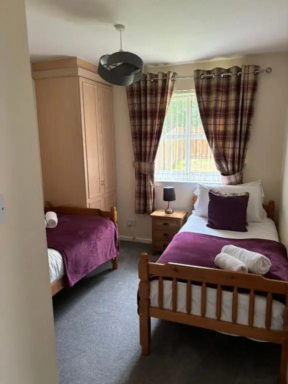 a bedroom with two beds and a window at Cairngorm Cottage in Aviemore