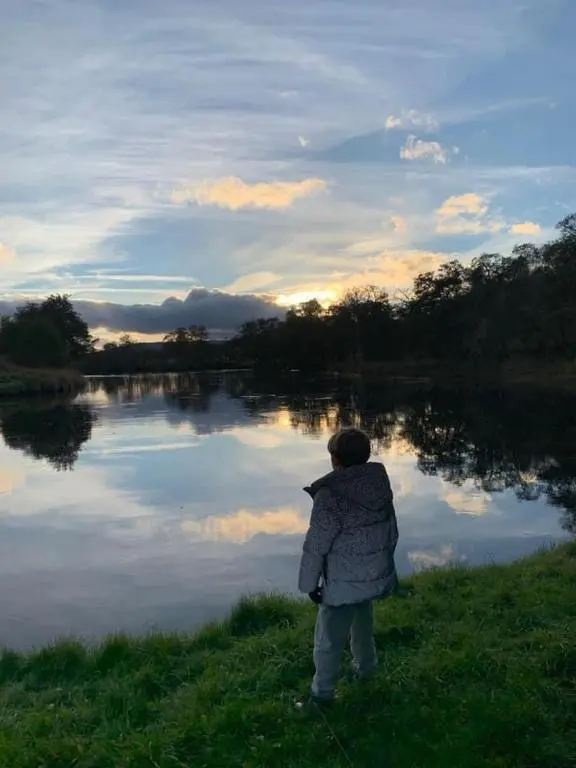 a young child standing by a lake with a kite at The One - Chalet in the Cairngorms in Boat of Garten
