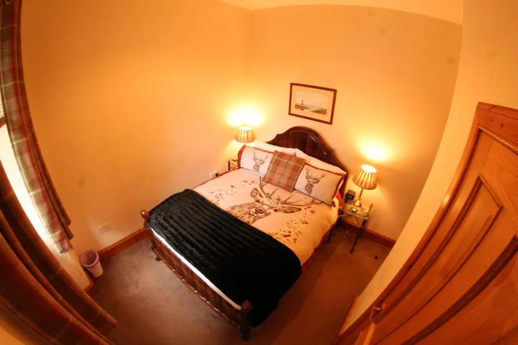 a small bedroom with a bed with two lamps at Glenfiddich in Nairn