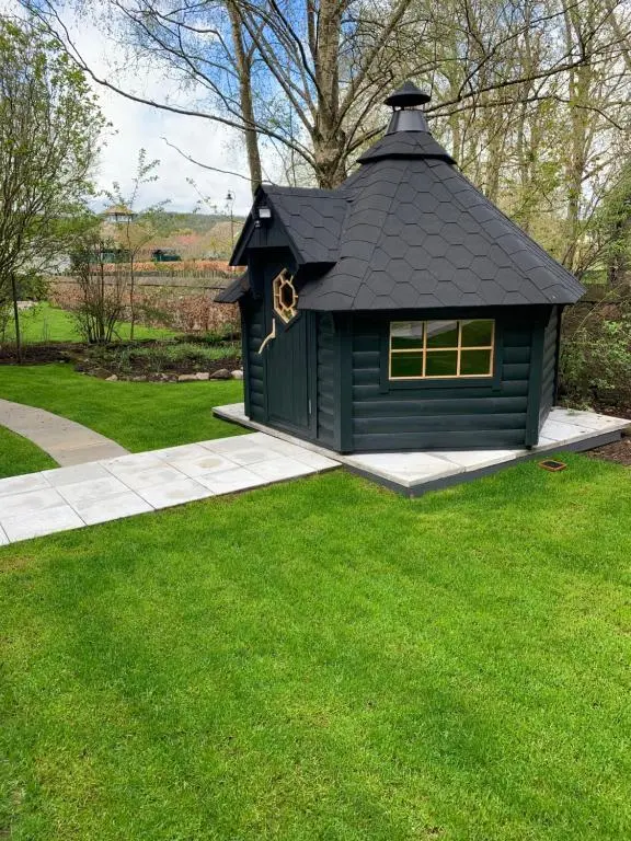 a black dog house with a window in the grass at Royal Snug & Wee Snug Cabins in Kincardine O\u02bcNeil