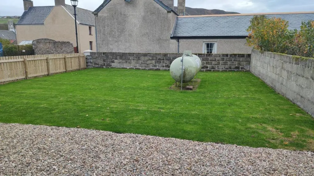 a backyard with a large yard with a stone wall at Dunvegan House in Helmsdale