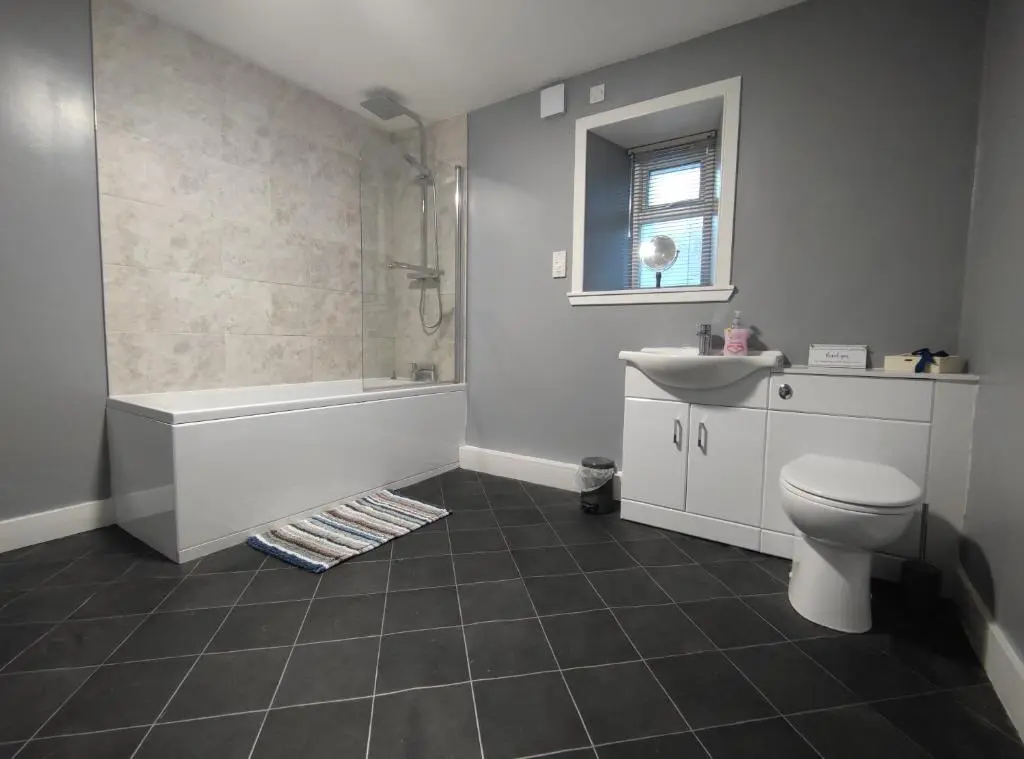 a bathroom with a tub and a toilet and a sink at Dunvegan House in Helmsdale