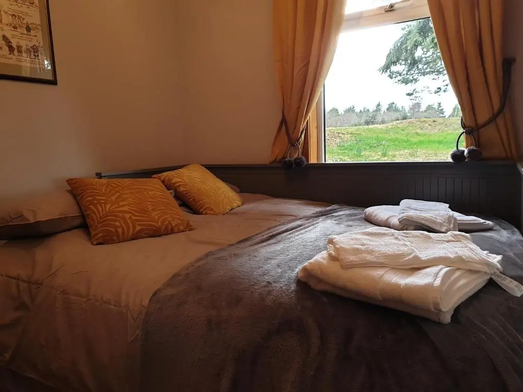a bed in a room with a window and towels on it at Craigbreck Farm Cottage in North Kessock