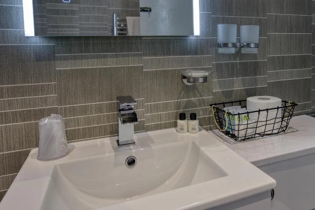a white sink in a bathroom with a mirror at Golspie Inn in Backies