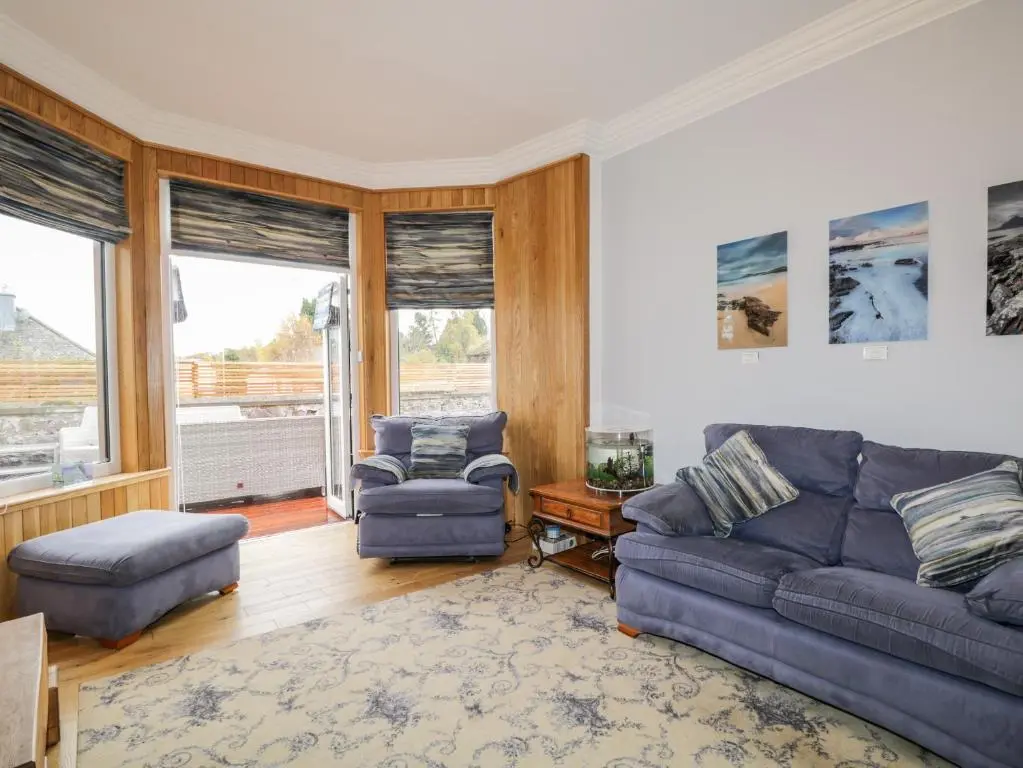 a living room with a couch and a chair at Orrinside in Muir of Ord