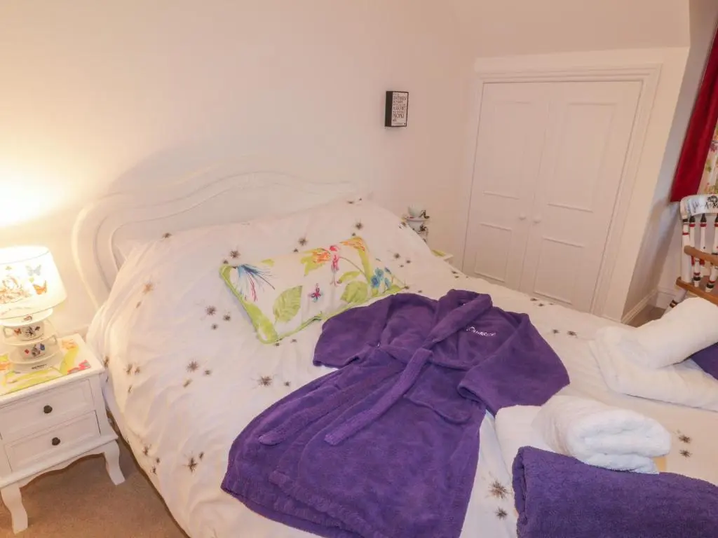 a bed with a purple robe laying on it at Orrinside in Muir of Ord
