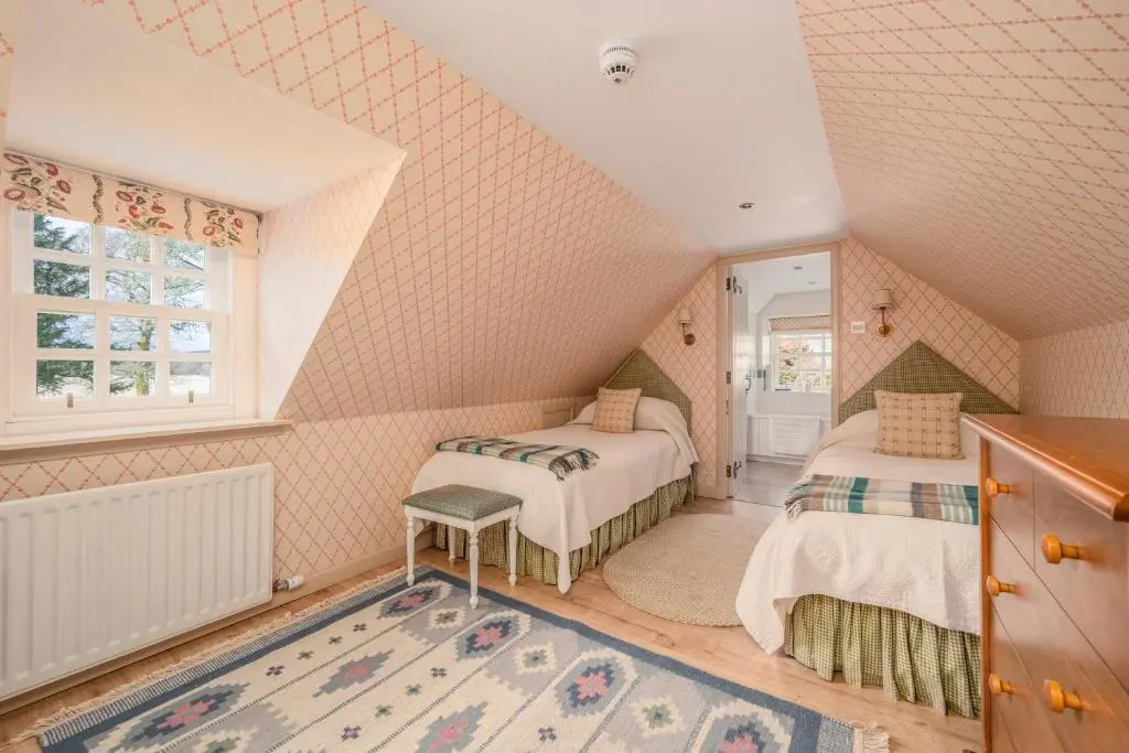 a attic bedroom with two beds and a window at Balnagown Estates Gardener's Cottage in Kildary