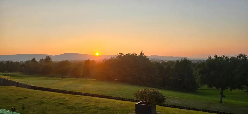 a sunset over a golf course with the sun setting at Brohar Annexe in Inverness