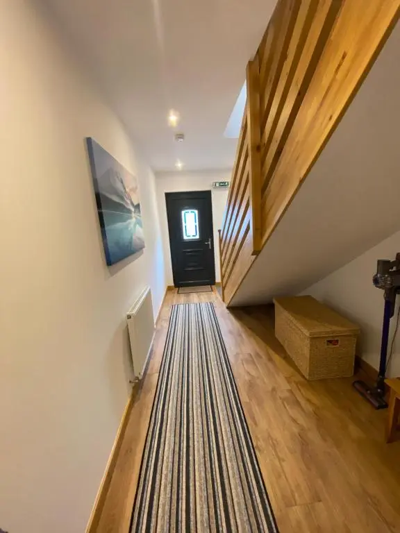 a hallway with a black door and a staircase with a rug at Brohar Annexe in Inverness
