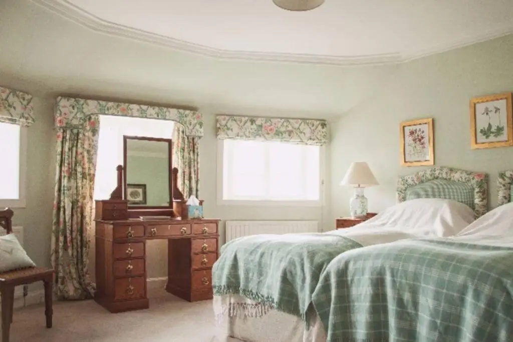 a bedroom with two beds and a dresser and a mirror at Garden Cottage, Fochabers in Fochabers