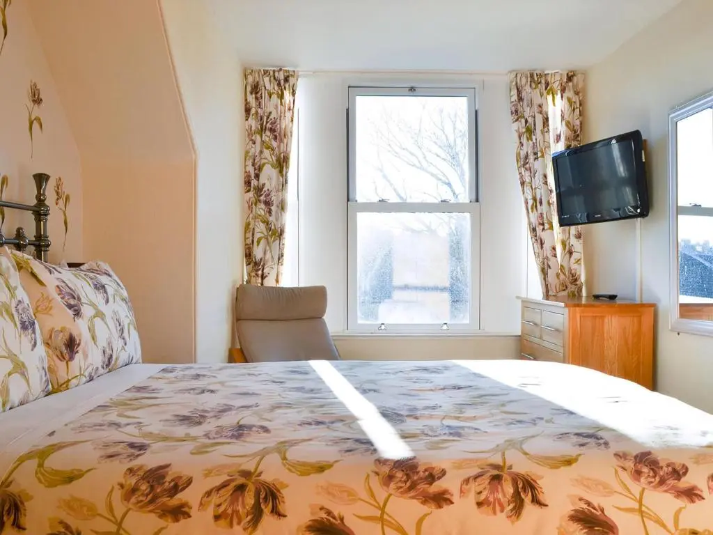 a bedroom with a bed and a television and a window at Brighton House in Nairn