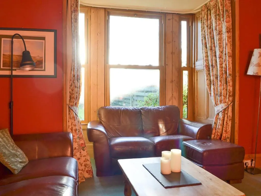 a living room with a leather couch and a table at Brighton House in Nairn