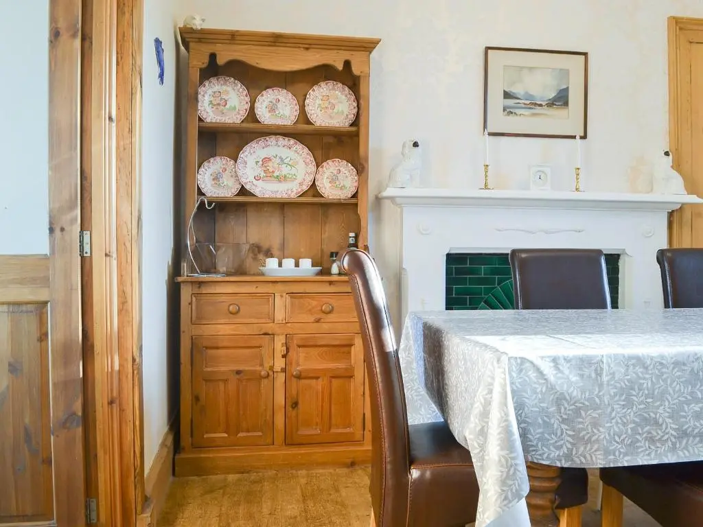 a dining room with a table and a shelf with plates at Brighton House in Nairn
