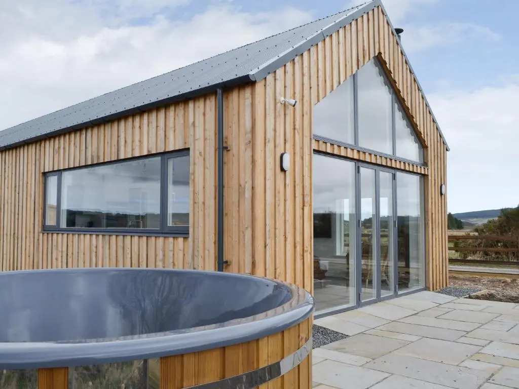 a wooden building with a tub in front of it at Muirtown Lodge in Keith