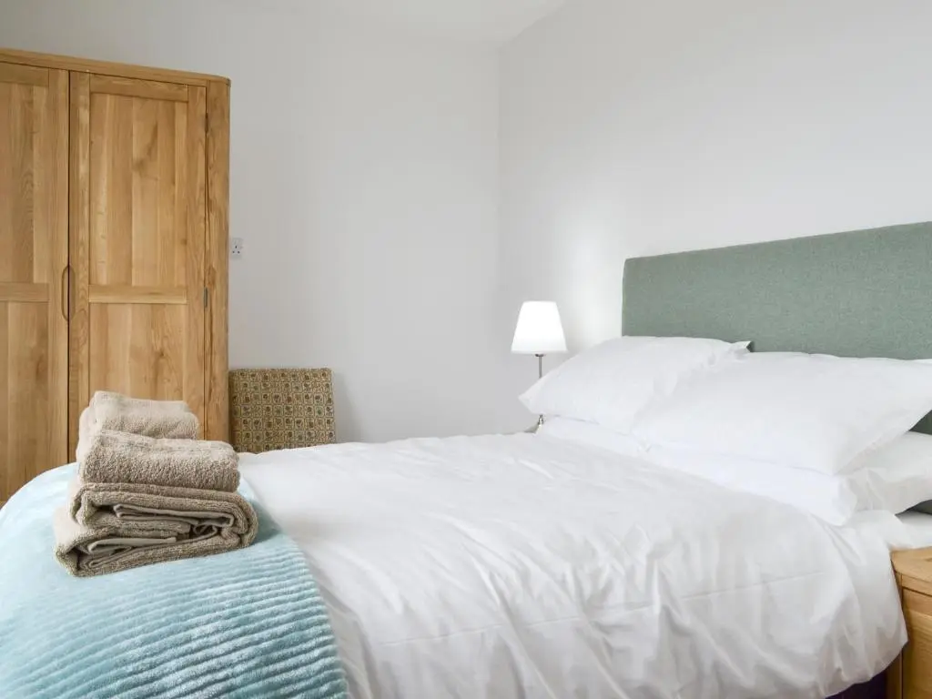 a bedroom with a large white bed and a wooden door at Muirtown Lodge in Keith