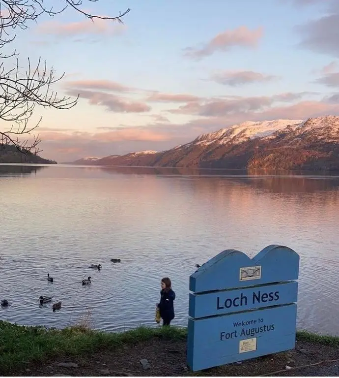 a child standing in a lake with ducks in the water at Loch Ness Pods in Fort Augustus