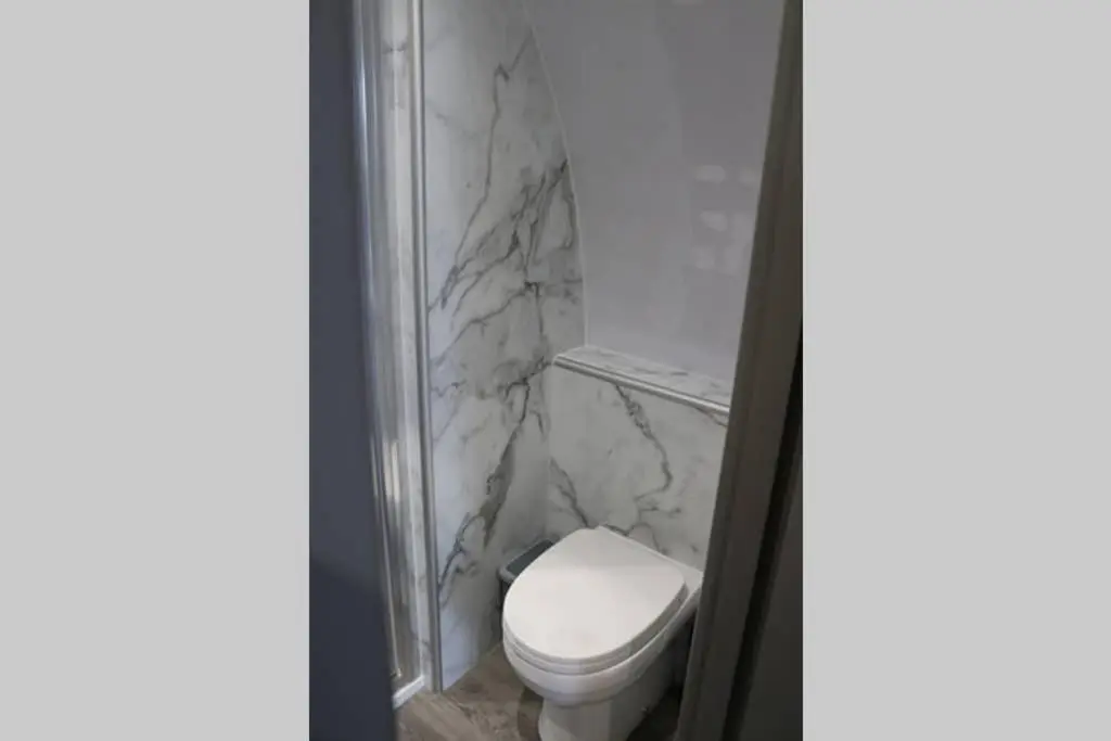 a bathroom with a white toilet and marble walls at Glampods Glamping Pod - meet Highland Cows and Sheep Elgin in Elgin