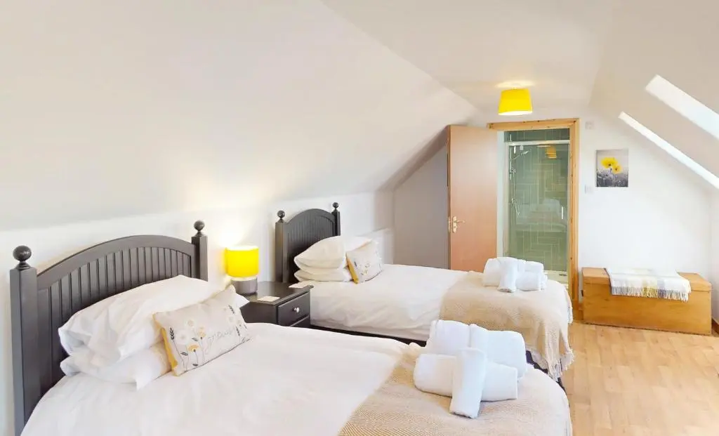 a bedroom with two beds with white sheets at Dalfern Lodge in Aviemore