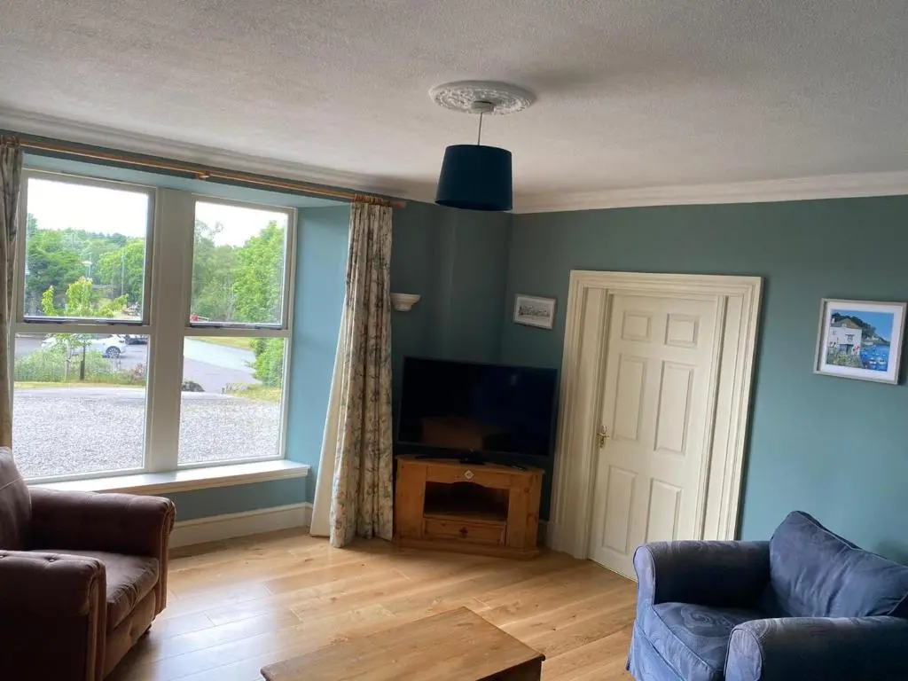 a living room with a couch and a television at Granite Cottage in Nethy Bridge