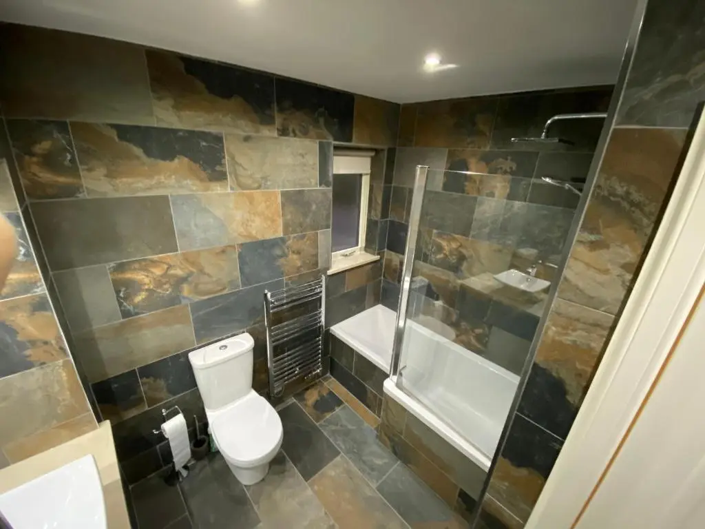 a bathroom with a toilet and a shower and a tub at Granite Cottage in Nethy Bridge