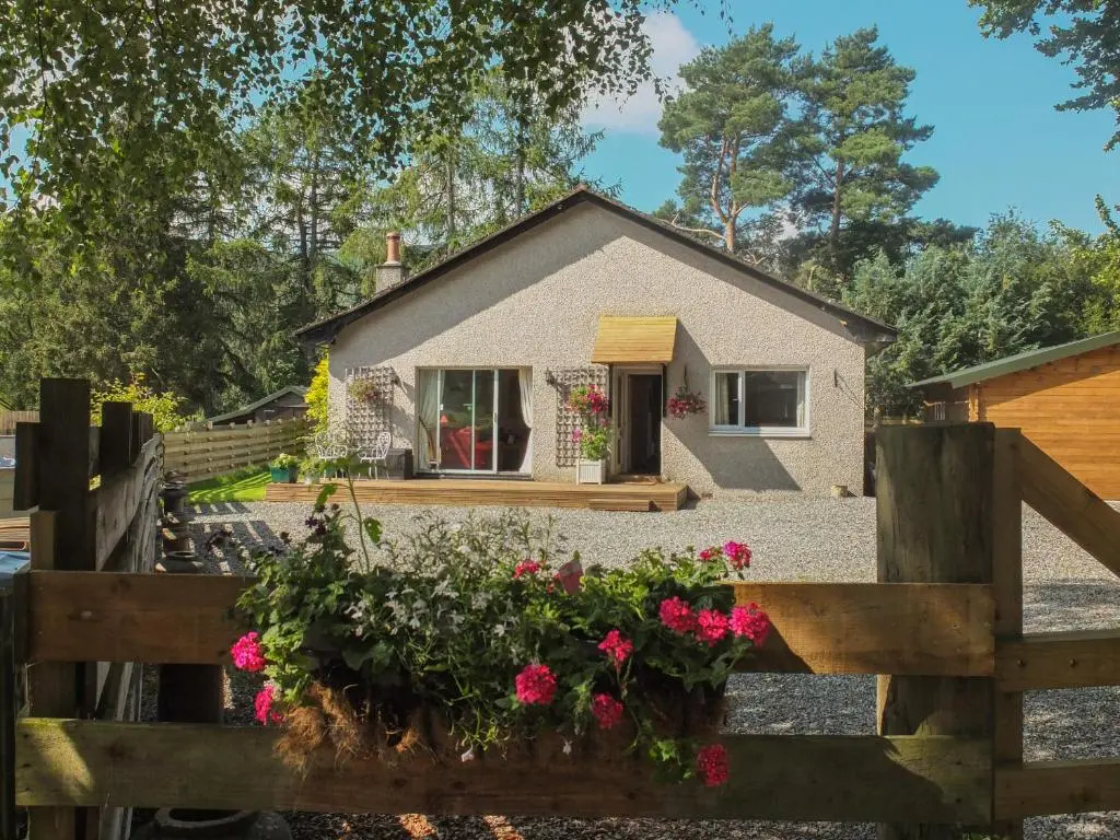a house with a fence and flowers in front of it at Beechwood Cottage in Pitlochry