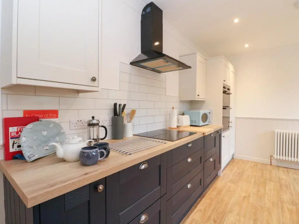 a kitchen with white cabinets and a wooden counter top at Beechwood Cottage in Pitlochry