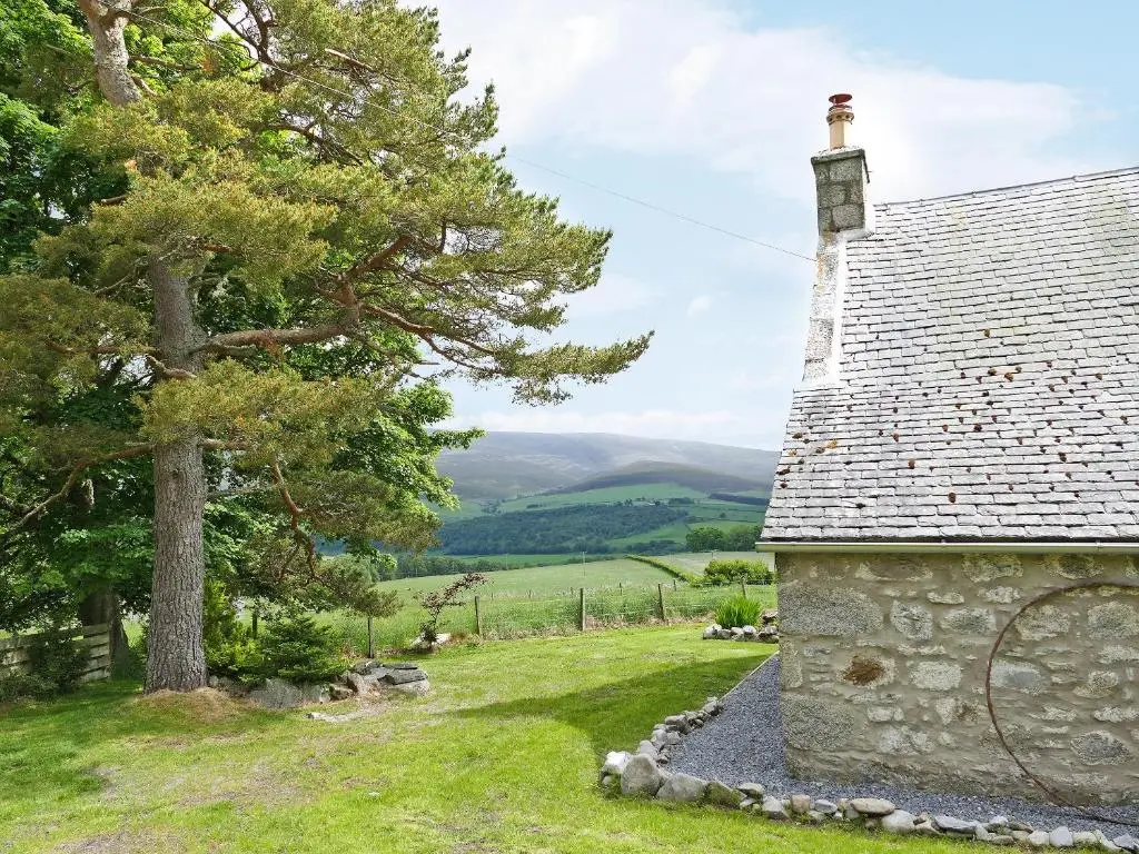 a stone building with a tree next to it at Easter Lettoch in Advie