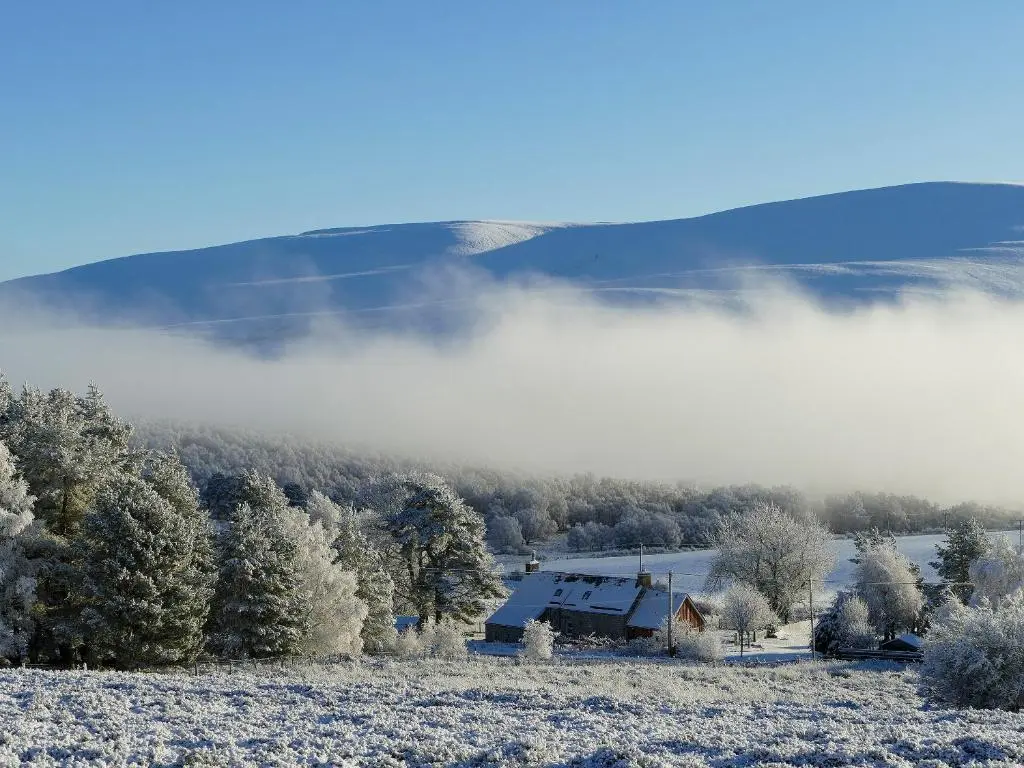 a house in a field with fog in the background at Easter Lettoch in Advie