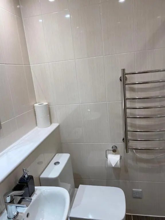 a white bathroom with a toilet and a sink at Waverley Inn Holiday Apartments in Inverness