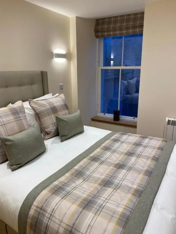 a bedroom with a large bed with pillows and a window at Waverley Inn Holiday Apartments in Inverness