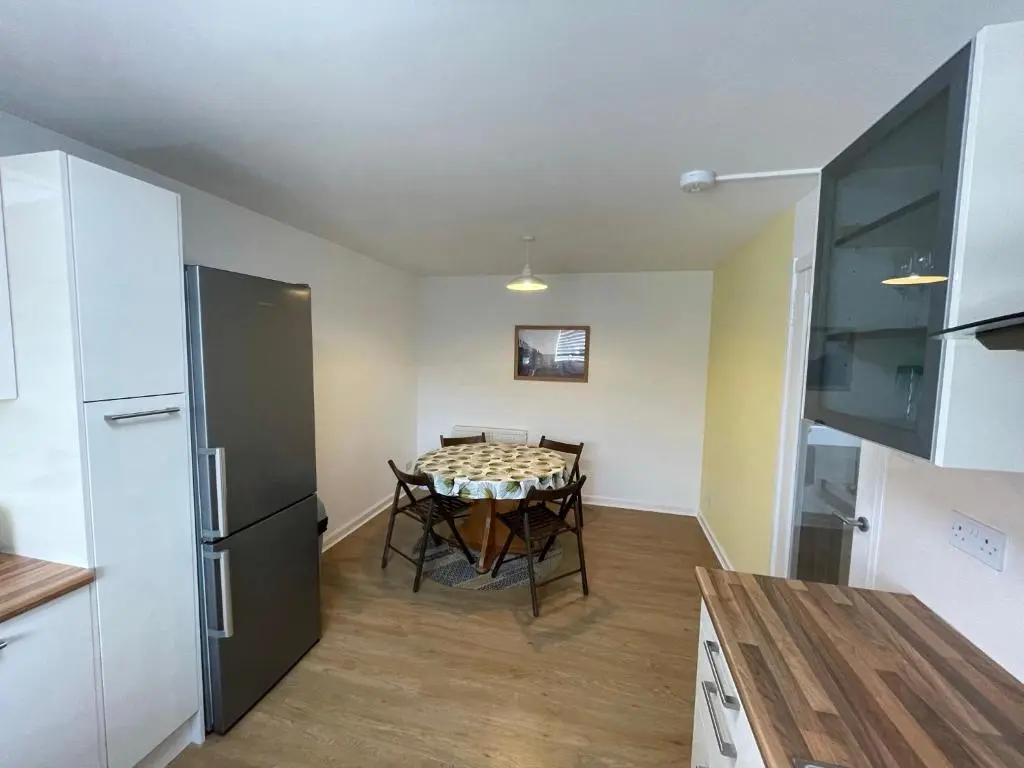 a kitchen and dining room with a table and a refrigerator at Lesmurdie Court, Serviced Accommodation Moray in Elgin