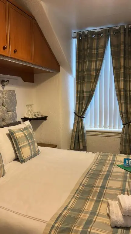 a bedroom with a bed and a window with curtains at Tay Villa in Inverness