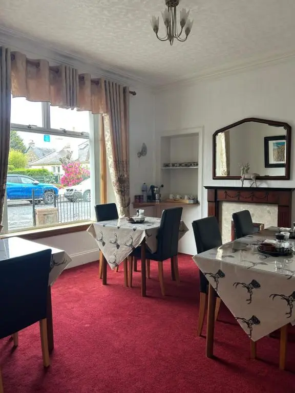 a dining room with a table and chairs and a mirror at Tay Villa in Inverness