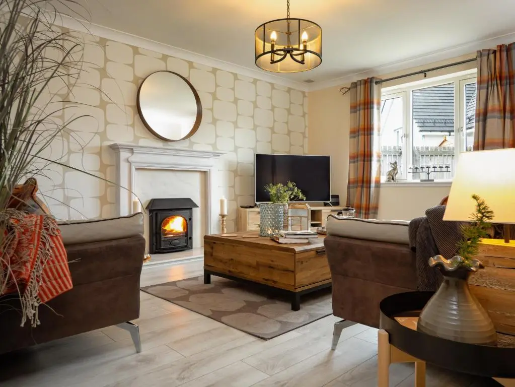 a living room with a couch and a fireplace at Eagle Lodge - Aviemore Lodges in Aviemore