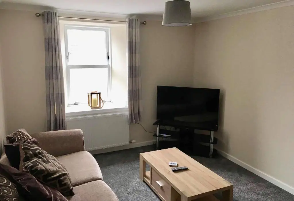 a living room with a couch and a television at 2 Bedroom Townhouse on NC500, Wick, Highland in Wick