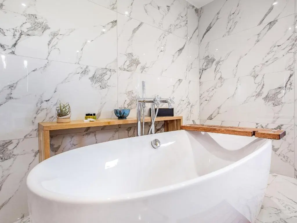 a white bath tub in a bathroom with marble walls at Morven View in Dunbeath