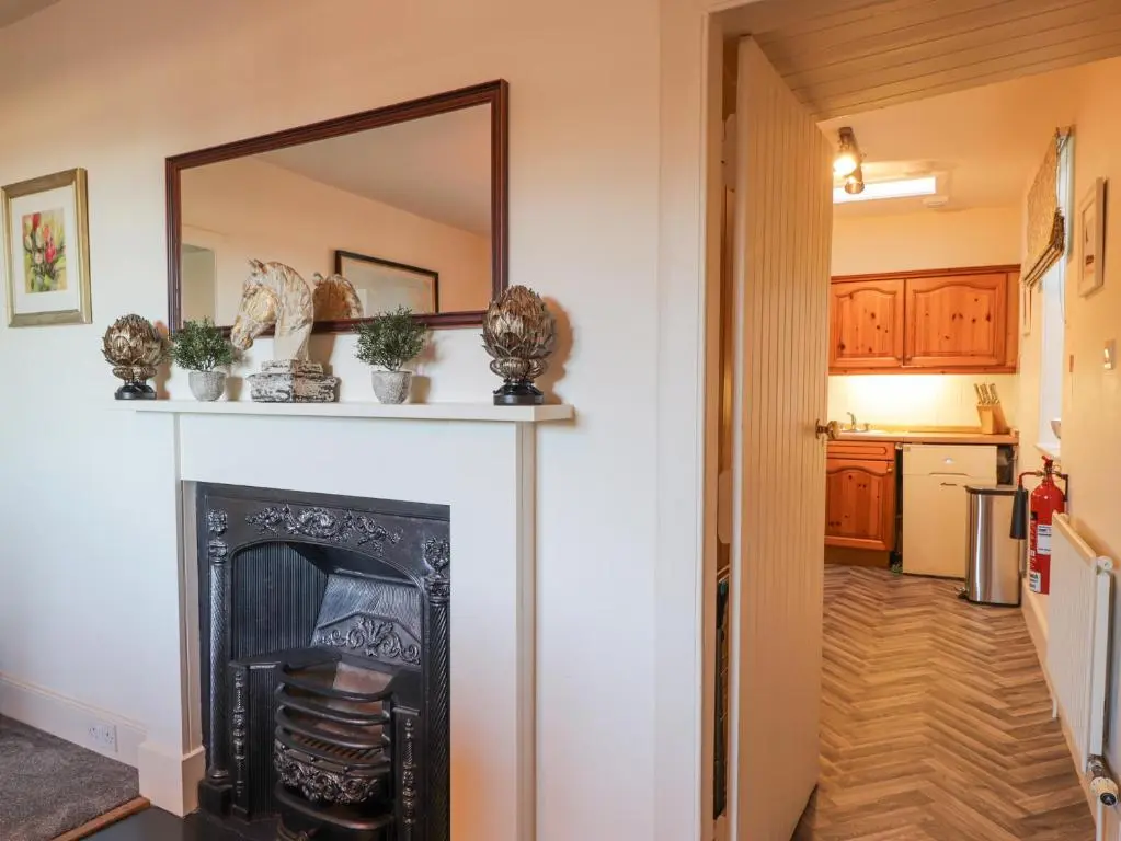 a living room with a fireplace and a mirror at Cormack Lodge - Brodie Castle in Forres