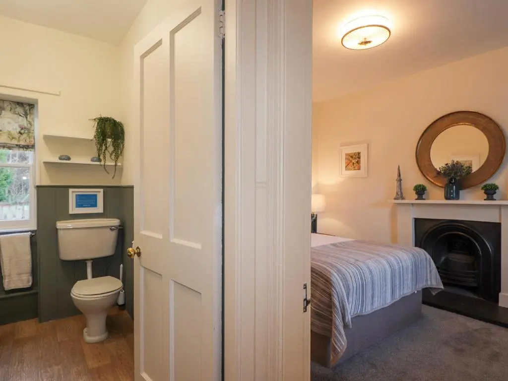 a bathroom with a toilet and a bed and a mirror at Cormack Lodge - Brodie Castle in Forres